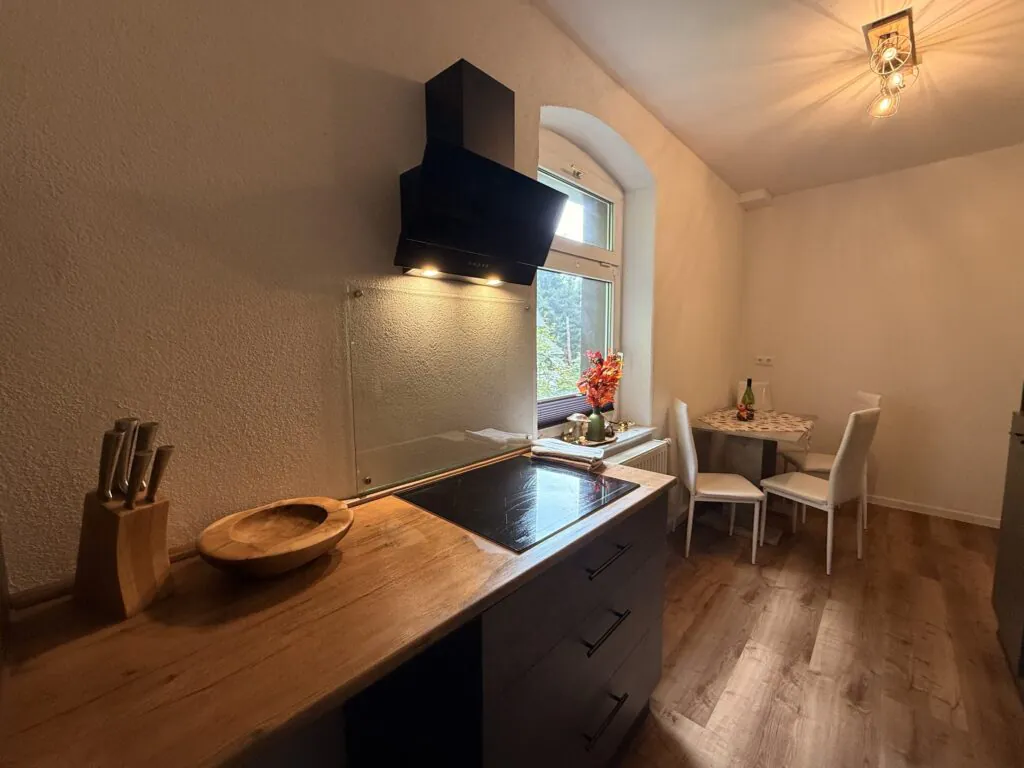 Küche mit Kochfeld und Blick zum Esstisch - Familienferienwohnung Felsenliebe, Hertigswalde